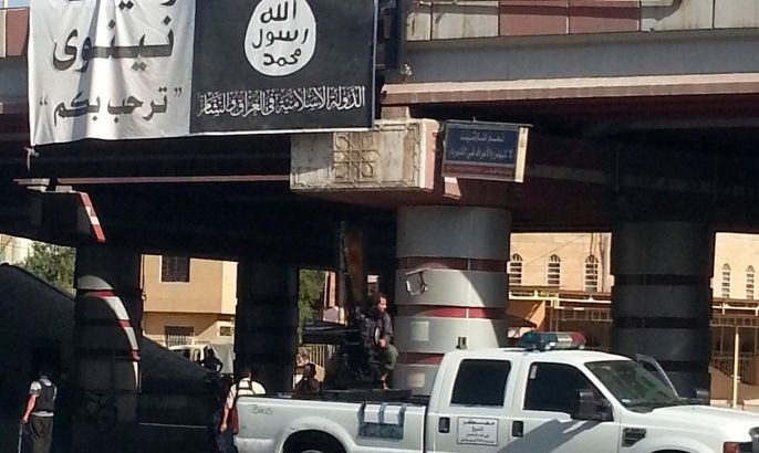 A fighter from the Islamic State, formerly known as the Islamic State of Iraq and the Levant (ISIL), mans an anti-aircraft gun mounted on the rear of a vehicle in Mosul July 16, 2014. The banner on the bridge reads: "Welcome to the State of Nineveh; There is no God but God and Mohammad is the Messenger of God". To match Exclusive MIDEAST-CRISIS/IRAQ-MOSUL REUTERS/Stringer /File Photo