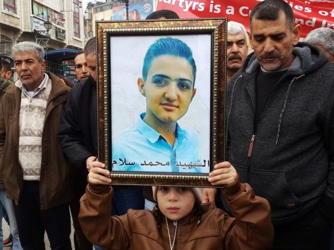 فلسطين رام الله 28 ديسمبر 2016 طفل من أقارب الشهيد محمد زيدان يحمل صورته خلال مظاهرة للمطالبة بتسليم جثامين الشهداء المحتجزة