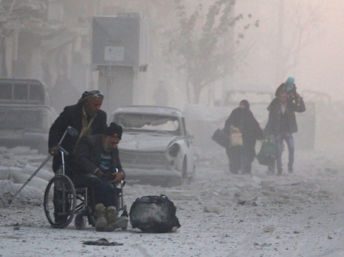 FILE PHOTO - A man on a wheelchair flees with others into the remaining rebel-held areas of Aleppo, Syria December 9, 2016. REUTERS/Abdalrhman Ismail /File Photo