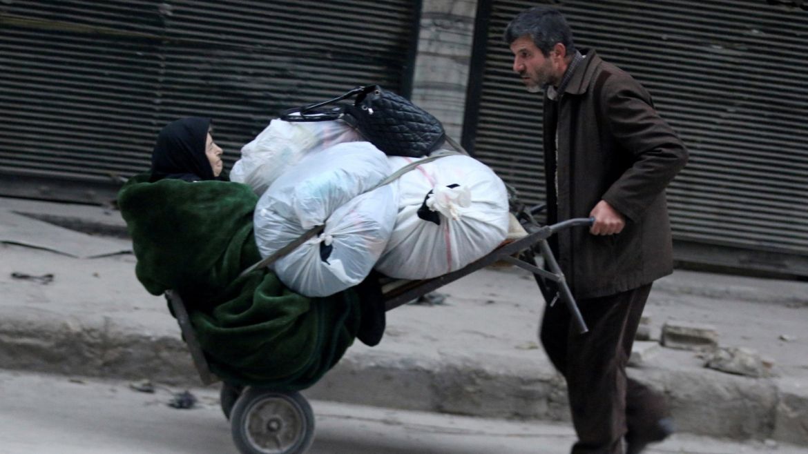 A man pushes a cart carrying an elderly woman and belongings as they flee deeper into the remaining rebel-held areas of Aleppo, Syria December 12, 2016. REUTERS/Abdalrhman Ismail