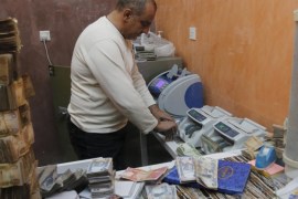 A man counts wads of Iraqi dinars on a money counting machine at a currency exchange shop in Baghdad December 21, 2015. REUTERS/Khalid al Mousily