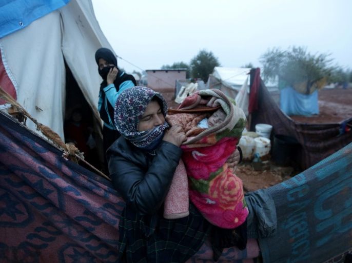 An internally displaced Syrian woman carries her child in the Bab Al-Salam refugee camp, near the Syrian-Turkish border, northern Aleppo province, Syria December 26, 2016. REUTERS/Khalil Ashawi
