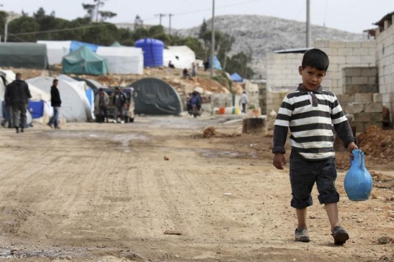 A boy walks holding a water jug in Bab Al-Hawa camp, near the Syria-Turkey border, February 15, 2014. REUTERS/Mouaz Al Omar (SYRIA - Tags: POLITICS CIVIL UNREST CONFLICT)
