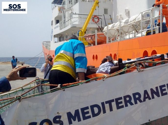 A migrant receives help when disembarking from the SOS Mediterranee ship Aquarius at the Italian island of Lampedusa in this handout received April 18, 2016. SOS Mediterranee/Handout via REUTERS ATTENTION EDITORS - THIS IMAGE WAS PROVIDED BY A THIRD PARTY. EDITORIAL USE ONLY. NO RESALES. NO ARCHIVE. REUTERS IS UNABLE TO INDEPENDENTLY VERIFY THIS IMAGE.