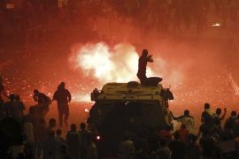 A riot police officer, on a armoured personnel carrier surrounded by anti-Mursi protesters (foreground), fires rubber bullets at members of the Muslim Brotherhood and supporters of ousted Egyptian President Mohamed Mursi along a road at Ramsis square, which leads to Tahrir Square, during clashes at a celebration marking Egypt's 1973 war with Israel, in Cairo in this October 6, 2013 file photo. REUTERS/Amr Abdallah Dalsh/Files