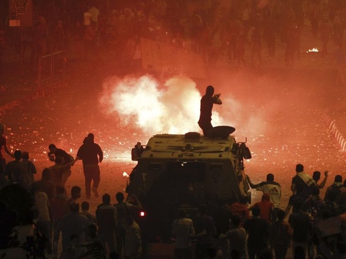 A riot police officer, on a armoured personnel carrier surrounded by anti-Mursi protesters (foreground), fires rubber bullets at members of the Muslim Brotherhood and supporters of ousted Egyptian President Mohamed Mursi along a road at Ramsis square, which leads to Tahrir Square, during clashes at a celebration marking Egypt's 1973 war with Israel, in Cairo in this October 6, 2013 file photo. REUTERS/Amr Abdallah Dalsh/Files