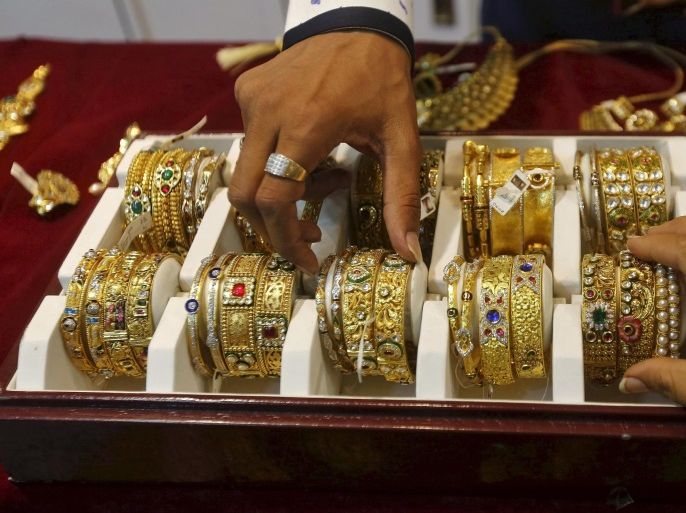 A salesman helps a customer (R) to select gold bangles at a jewelry showroom in Mumbai, India, in this May 21, 2015 file photo. India's overseas gold purchases are likely to hit a more than two-year low in February, as rising prices and hopes for a cut in import taxes keep buyers away, industry sources said. REUTERS/Shailesh Andrade/Files