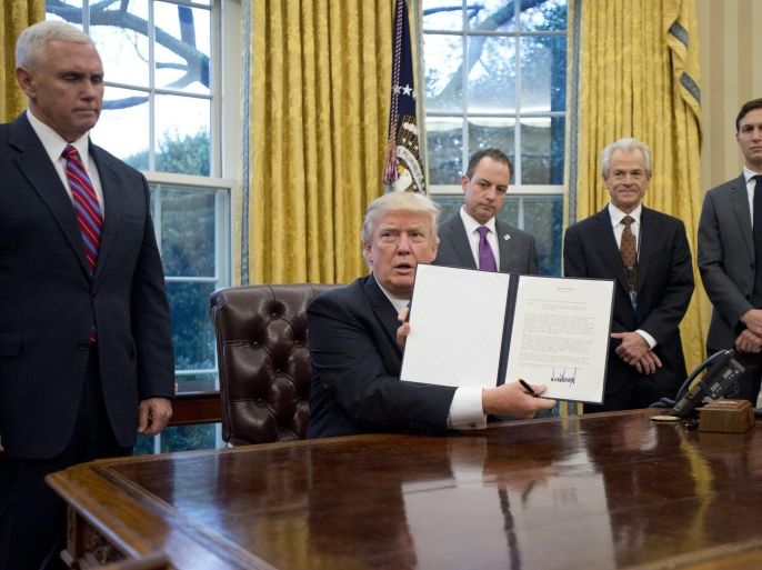 US President Donald J. Trump shows the Executive Order withdrawing the US from the Trans-Pacific Partnership (TPP) after signing it in the Oval Office of the White House in Washington, DC, USA, 23 January 2017. They concerned the withdrawal of the United States from the Trans-Pacific Partnership (TPP), a US Government hiring freeze for all departments but the military, and 'Mexico City' which bans federal funding of abortions overseas. Standing behind the President, f