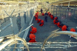 Detainees in orange jumpsuits sit in a holding area while watched by U.S. military police at the temporary Camp X-Ray, which was later closed and replaced by Camp Delta, inside Guantanamo Bay naval base in a January 11, 2002 file photo. President Barack Obama launched a final push on Tuesday to persuade Congress to close the U.S. military prison at Guantanamo Bay, Cuba, but lawmakers, opposed to rehousing detainees in the United States, declared his plan a non-starter.