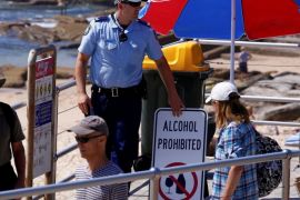 A policeman adjusts a sign declaring that no alcohol is allowed to be brought onto Sydney's Bondi Beach on Christmas Day in Australia, December 25, 2016. REUTERS/David Gray