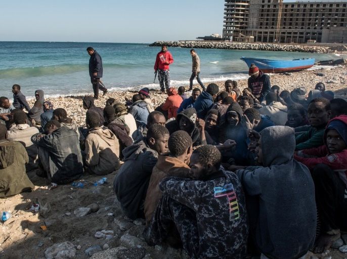 Migrants, who were on a boat which capsized on Wednesday, sit on a beach after policemen arrested them in Tripoli, Libya, January 4, 2017. Picture taken January 4, 2017. REUTERS/Stringer EDITORIAL USE ONLY. NO RESALES. NO ARCHIVE.