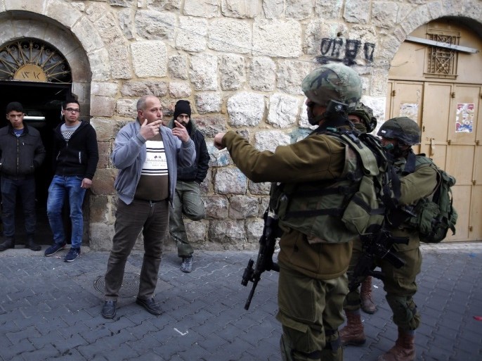 Israeli soldiers on patrol stop Palestinians at the Old City of Hebron, in the West Bank, 14 January 2017.