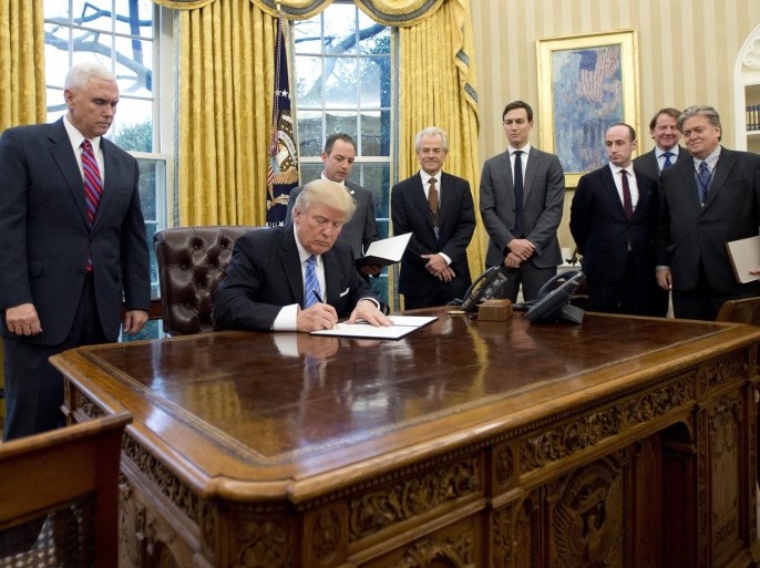 US President Donald J. Trump signs the first of three Executive Orders in the Oval Office of the White House in Washington, DC, USA, 23 January 2017. They concerned the withdrawal of the United States from the Trans-Pacific Partnership (TPP), a US Government hiring freeze for all departments but the military, and "Mexico City" which bans federal funding of abortions overseas. Standing behind the President, from left to right: US Vice President Mike Pence; White House Ch