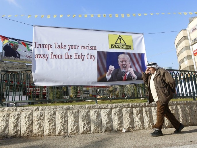 A Palestinian man passes a protest banner featuring an image of US President-elect Donald J. Trump and the slogan 'Trump: Take your racism away from the Holy City', against Trump's intention to move the US Embassy to Jerusalem, in the west bank City of Nablus, 19 January 2017.