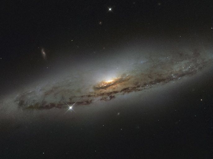 The spiral galaxy NGC 4845, located over 65 million light-years away in the constellation of Virgo (The Virgin) is shown in this NASA/ESA Hubble Space Telescope image released on January 8, 2016. The galaxy�s orientation clearly reveals the galaxy�s striking spiral structure: a flat and dust-mottled disc surrounding a bright galactic bulge. NGC 4845�s glowing center hosts a gigantic version of a black hole, known as a supermassive black hole. REUTERS/NASA/Handout FOR E