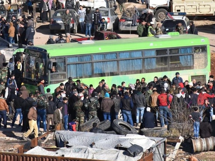 A handout photograph released by the official Syrian Arab News Agency (SANA) showing people standing near a government green bus during evacuation of fighters and their families from rebel-held zones in Aleppo, Syria, 15 December 2016. The evacuation of Aleppo began on 15 December as the first ambulances and buses extracted the sick and wounded from final rebel-held zones in the northern Syrian city, the Red Cross NGO said. Reports state the first batch of 951 gunmen and their families were evacuated via al-Ramouseh crossing to Aleppo southwestern countryside. EPA/SANA HANDOUT HANDOUT EDITORIAL USE ONLY/NO SALES