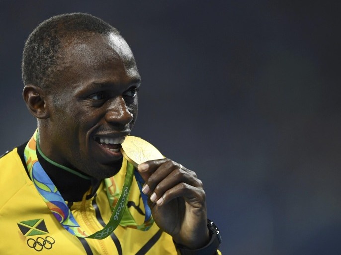 2016 Rio Olympics - Athletics - Victory Ceremony - Men's 4 x 100m Relay Victory Ceremony - Olympic Stadium - Rio de Janeiro, Brazil - 20/08/2016. Gold medalist Usain Bolt (JAM) of Jamaica bites his medal. REUTERS/Dylan Martinez TPX IMAGES OF THE DAY. FOR EDITORIAL USE ONLY. NOT FOR SALE FOR MARKETING OR ADVERTISING CAMPAIGNS.
