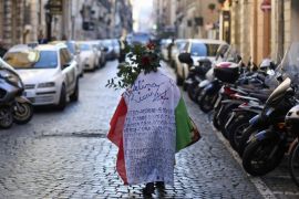 A woman walks while wearing an Italian national flag before a demonstration organised by "People from the Pitchfork Movement" to protest against economic insecurity and the government in downtown Rome December 18, 2013. The "pitchfork" movement was originally a loosely organised group of farmers from Sicily. REUTERS/Alessandro Bianchi (ITALY - Tags: BUSINESS CIVIL UNREST POLITICS EMPLOYMENT)