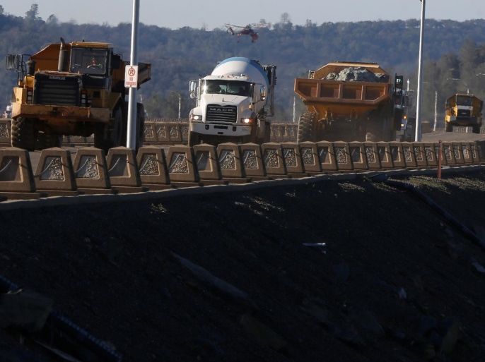 Trucks carry rocks as water is released from the Lake Oroville Dam after an evacuation order was lifted for communities downstream from the dam in Oroville, California, U.S. February 14, 2017. REUTERS/Jim Urquhart