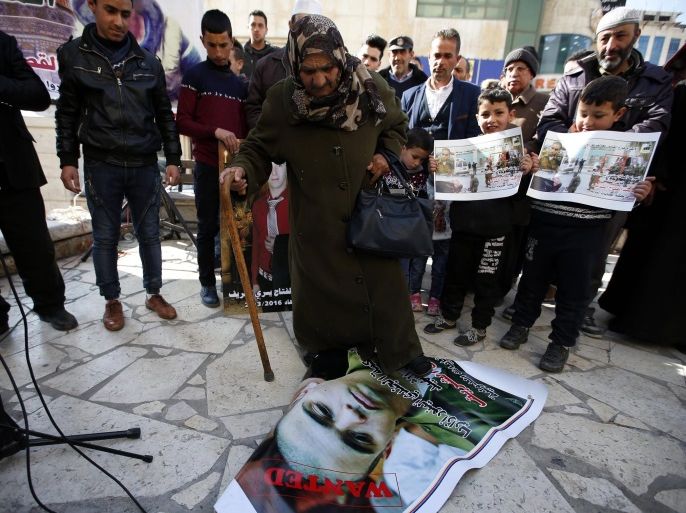 A Palestinian woman (C) stands on a photo of Israeli soldier Elor Azaria during a protest in Hebron, 21 January 2017. Israeli soldier Sgt. Elor Azaria who fatally shot an unarmed and immobilized Palestinian man was sentenced to 18 months in prison on 21 February at a military court in Tel Aviv.