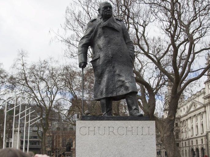 A woman is photographed by her companion as she poses with a Union Jack flag under a statue of former British Prime Minister Winston Churchill in London, March 22, 2015. REUTERS/Neil Hall