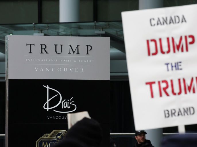 Protesters hold signs outside of the Trump International Hotel and Tower during its grand opening in Vancouver, British Columbia, Canada February 28, 2017. REUTERS/David Ryder