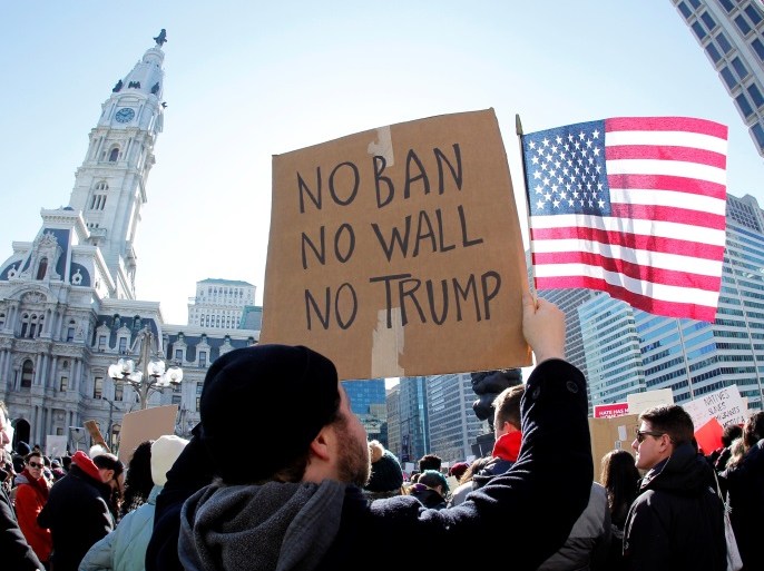 Protester Brandon McTear holds a sign and the American Flag as demonstrators gather to protest against U.S President Donald Trump's executive order banning refugees and immigrants from seven primarily Muslim countries from entering the United States during a rally in Philadelphia, Pennsylvania, U.S. February 4, 2017 REUTERS/Tom Mihalek
