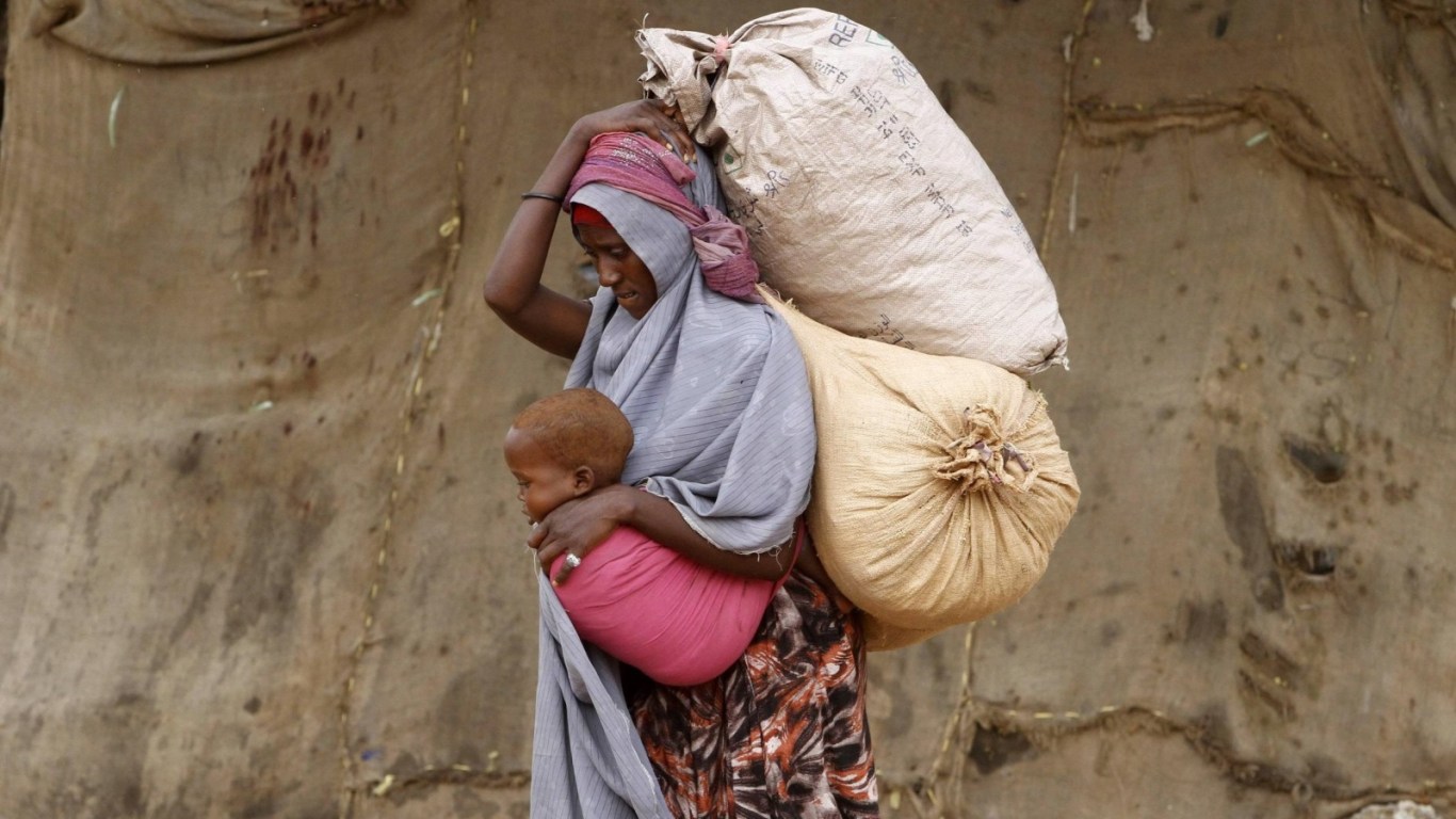 A displaced Somali woman carries a child and her belongings as she arrives at a temporary dwelling after fleeing famine in the Marka Lower Shebbele regions to the capital Mogadishu, September 20, 2014. The United Nations said this month more than a million people in war-ravaged Somalia were struggling to meet daily nutritional needs. The roughly 130,000 people displaced from their homes this year alone are bearing the brunt of the crisis. REUTERS/Feisal Omar (SOMALIA - Tags: DISASTER SOCIETY POVERTY CIVIL UNREST TPX IMAGES OF THE DAY)