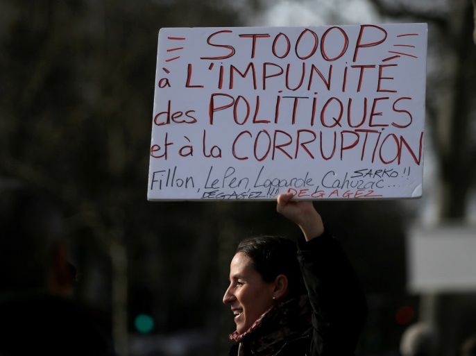 A woman holds a banner as she attends a gathering against the corruption of elected representatives at Place de la Republique in Paris, France February 25, 2017. The banner reads