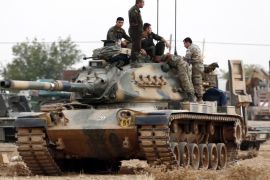 Turkish soldiers stand on tanks at the Syrian border