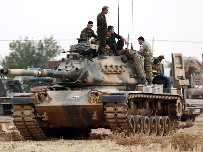 Turkish soldiers stand on tanks at the Syrian border