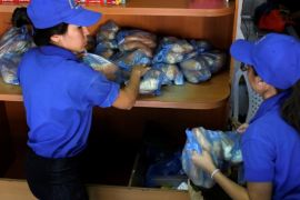 Saleswomen grab bags of bread at a bakery in Caracas, Venezuela March 17, 2017. REUTERS/Marco Bello