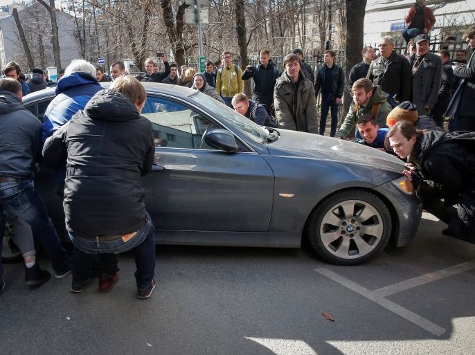 Opposition supporters move a car to block the road to prevent the van transporting detained anti-corruption campaigner and opposition figure Alexei Navalny during a rally in Moscow, Russia, March 26, 2017. REUTERS/Maxim Shemetov