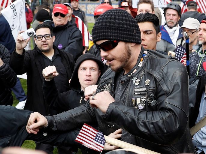 A man (center L) punches a supporter of U.S. President Donald Trump during a