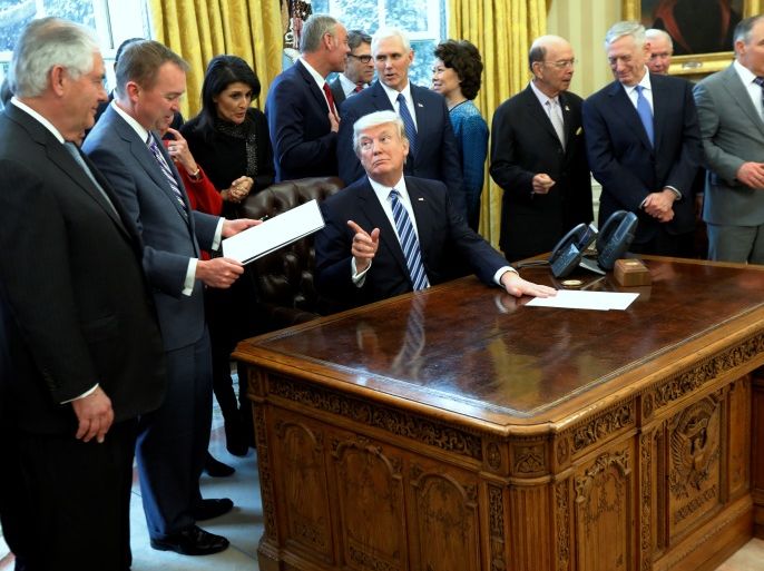 U.S. President Donald Trump, surrounded by his cabinet, looks up at Office of Management and Budget (OMB) Director Mick Mulvaney (2nd L) as he reads the executive order entitled
