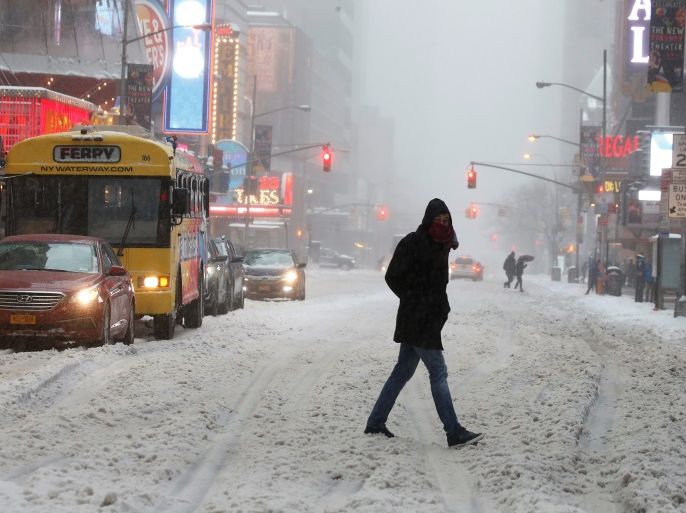A commuter walks across a street during a snowstorm in Times Square in the Manhattan borough of New York, New York, U.S. March 14, 2017. REUTERS/Carlo Allegri