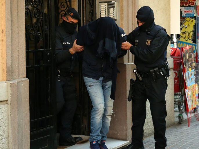 Spanish police lead a suspect from an apartment building during a sweeping operation at some 12 locations against Islamist militants in which eight people were arrested in Barcelona, Spain, April 25, 2017. REUTERS/Albert Gea