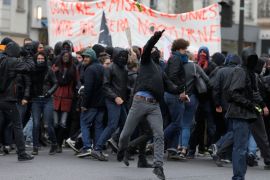 Masked demontrators throw projectiles to police during a protest march
