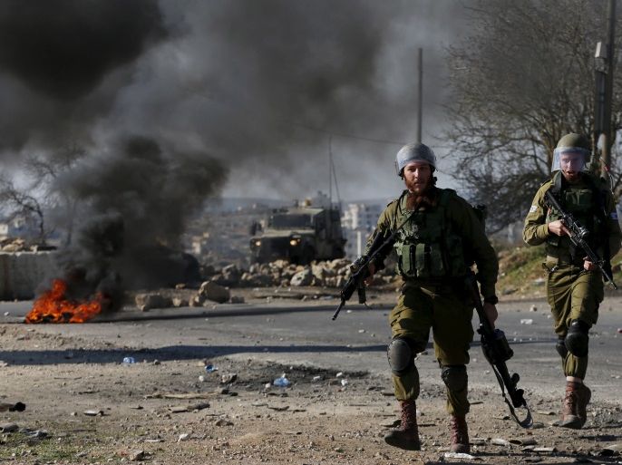 Israeli soldiers walk during clashes with Palestinians in the West Bank village of Silwad, near Ramallah, December 11, 2015. REUTERS/Ammar Awad