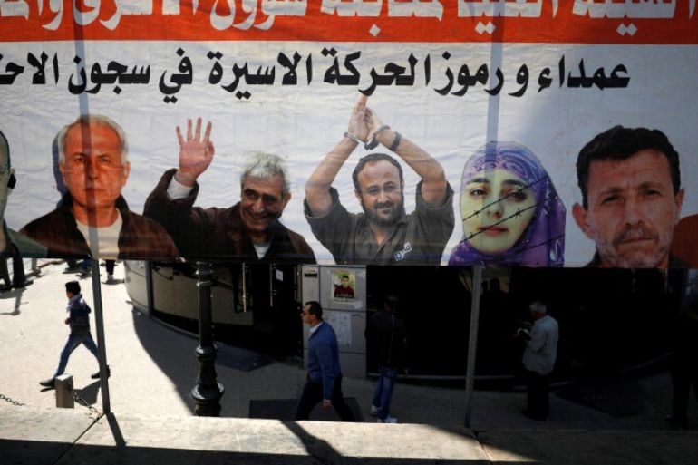 People walk past a poster depicting Palestinian prisoners held in Israeli jails, in the West Bank city of Ramallah April 17, 2017. REUTERS/Mohamad Torokman