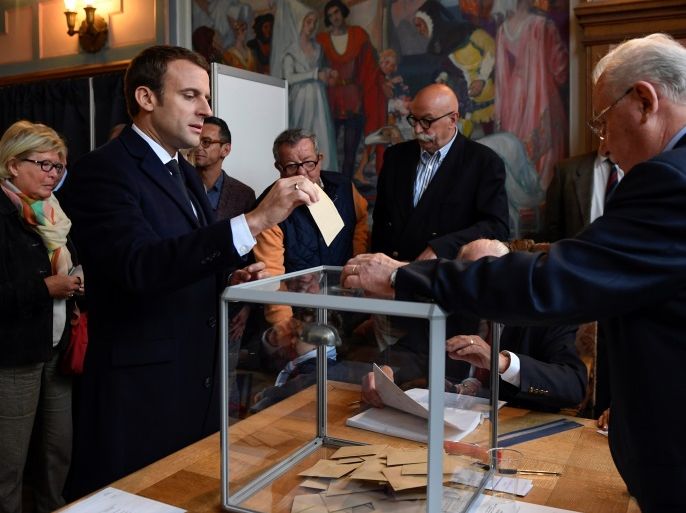 Emmanuel Macron (2ndL), head of the political movement En Marche !, or Onwards !, and candidate for the 2017 French presidential election, casts his ballot in the first round of 2017 French presidential election at a polling station in Le Touquet, northern France, April 23, 2017. REUTERS/Eric Feferbert/Pool
