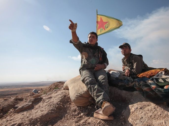 KOBANE, SYRIA - JUNE 20: (TURKEY OUT) A Kurdish People's Protection Units, or YPG fighters sit near a check point in the outskirts of the destroyed Syrian town of Kobane, also known as Ain al-Arab, Syria. June 20, 2015. Kurdish fighters with the YPG took full control of Kobane and strategic city of Tal Abyad, dealing a major blow to the Islamic State group's ability to wage war in Syria. Mopping up operations have started to make the town safe for the return of reside