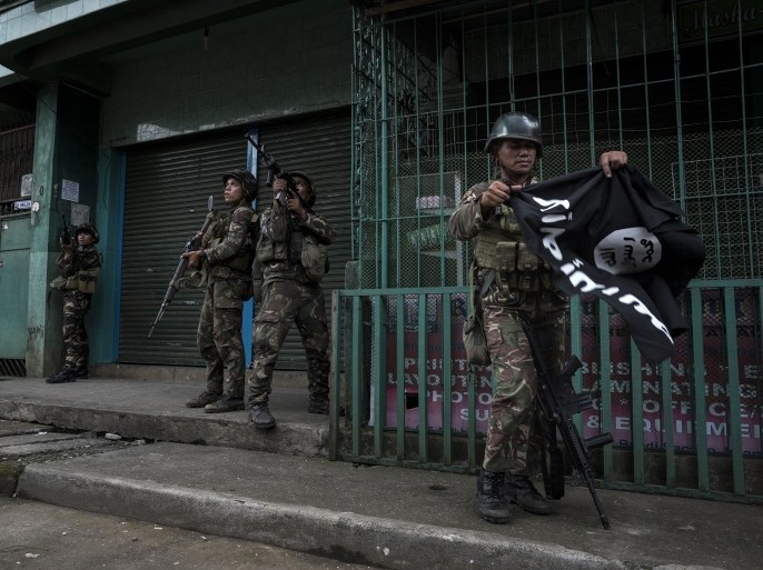 MARAWI CITY, PHILIPPINES - MAY 26: A soldier carrying a captured ISIS flag while clearing a city street of militants on May 26, 2017 in Marawi city, southern Philippines. Filipino officials announced on Friday that foreign fighters were among the Islamist militants killed in Marawi city during gun battles between ISIS-linked militants and security troops this week. President Rodrigo Duterte had declared 60 days of martial law in Mindanao on Tuesday after local terrorist groups Maute Group and Abu Sayyaf rampaged through the southern city and said that martial law could be extended across the Philippines to enforce order, allowing the detention of people without charge. Based on reports, at least 31 ISIS-linked militants and 13 government troopers have been killed so far while thousands of residents continue to flee from Malawi city. (Photo by Jes Aznar/Getty Images)