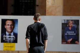 A French national living in Israel looks at posters depicting the candidates of the 2017 French presidential election, Emmanuel Macron and Marine Le Pen, outside a polling station in Jerusalem May 7, 2017. REUTERS/Ronen Zvulun