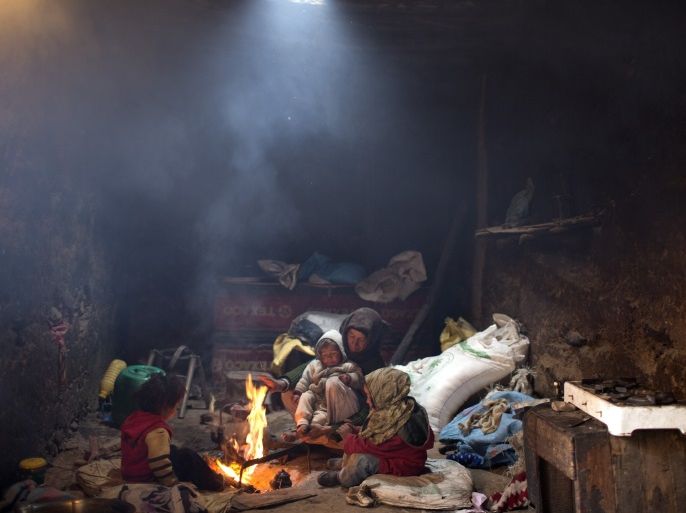 A woman and her children warm themselves around a fire in their home in Tilmi village in the High Atlas region of Morocco February 13, 2015. The snowy foothills of the High Atlas mountains in Morocco are home to several Berber villages where the inhabitants make their living by farming, baking bread in traditional ovens, herding cattle, and the making and selling of honey, olive oil and pottery. Extreme weather fluctuations and erosion that causes flooding and landslides have led to a drop in agricultural productivity, the United Nations said. REUTERS/Youssef Boudlal (MOROCCO - Tags: TRAVEL SOCIETY TPX IMAGES OF THE DAY)ATTENTION EDITORS: PICTURE 06 OF 24 FOR WIDER IMAGE PACKAGE 'LIFE IN THE ATLAS MOUNTAINS'TO FIND ALL IMAGES SEARCH 'ATLAS BOUDLAL'