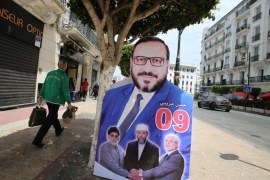 A man walks past an election poster of Hassan Aribi, who heads the list of the Islamist parties alliance,