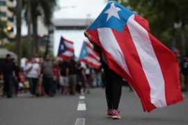 A person carries a Puerto Rican national flag during a protest against the government's austerity measures as Puerto Rico faces a deadline on Monday to restructure its $70 billion debt load or open itself up to lawsuits from creditors, in San Juan, Puerto Rico May 1, 2017. REUTERS/Alvin Baez