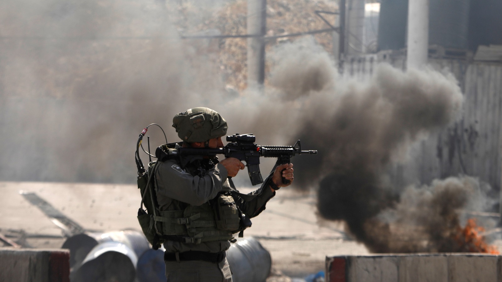 أحد جنود الاحتلال يطلق النار على متظاهرين فلسطينيين قرب حاجز قلنديا (رويترز)