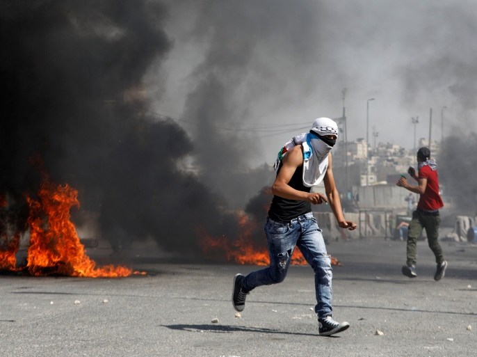 A Palestinian protester runs for cover during clashes with Israeli troops at a protest in support of Palestinian prisoners on hunger strike in Israeli jails, near Qalandiya checkpoint near the West Bank city of Ramallah May 22, 2017. REUTERS/Mohamad Torokman