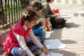 يسارع الأطفال لتعلم الرسم من الرسامين بالشارع. (تصوير خاص للرسامين بالشارع وهم يفترشون الأرض بجوارهم الأطفال يتعلمون الرسم ـ حديقة الحيوان ـ الجيزة ـ مصر ـ مايو 2017).